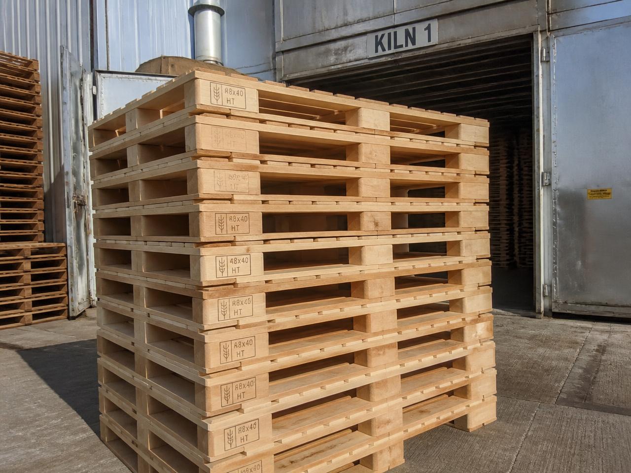 Heat-treated 48x40 stringer pallets stamped for export stacked outside a kiln