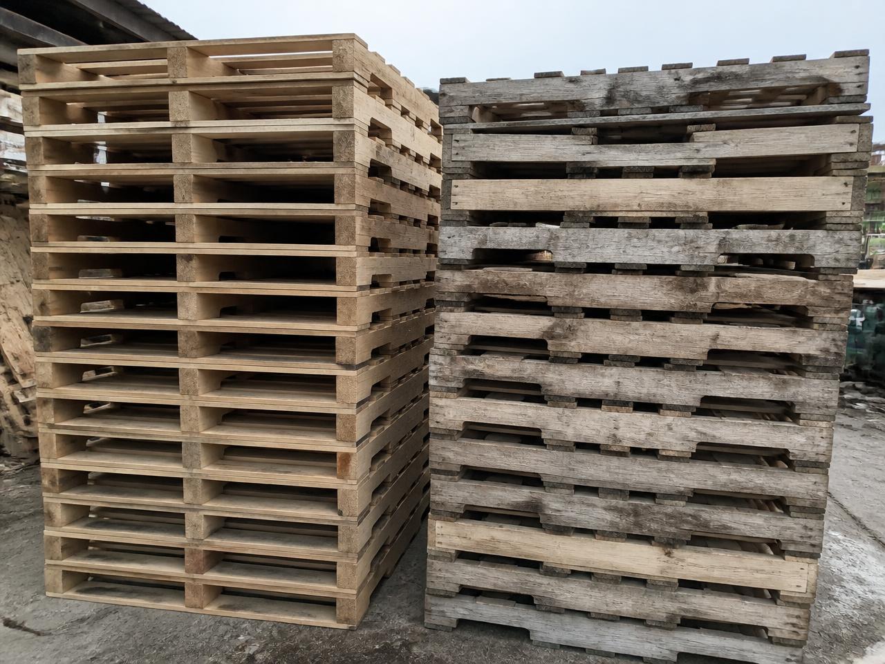 Sorted stacks of Grade A and Grade B used 48x40 GMA stringer pallets in a recycling yard